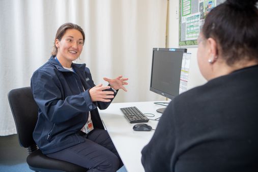 A corrections psychologist at a desk having a conversation